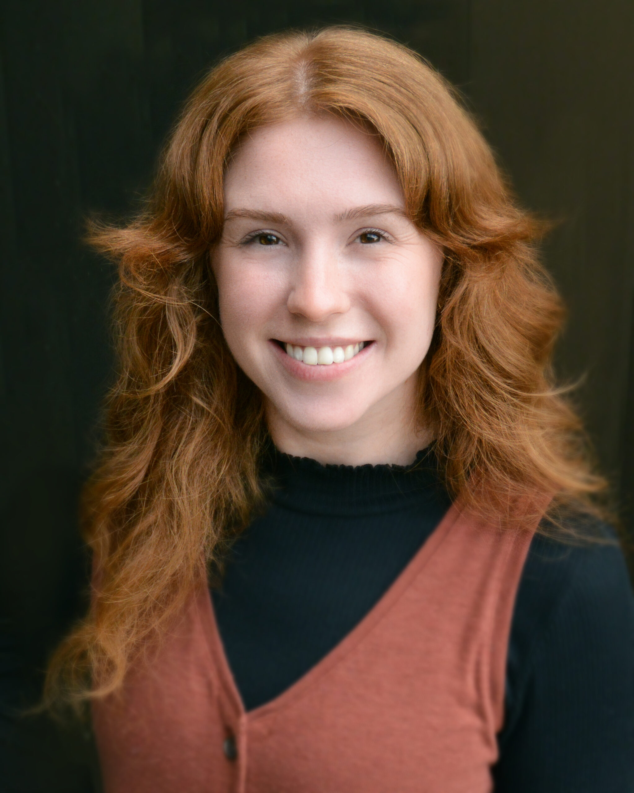 A photo of Ali, a woman with red hair, smiling.